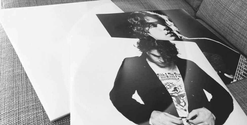 black and white photo of a new john mayer record on the inserts strewn across a grey couch
