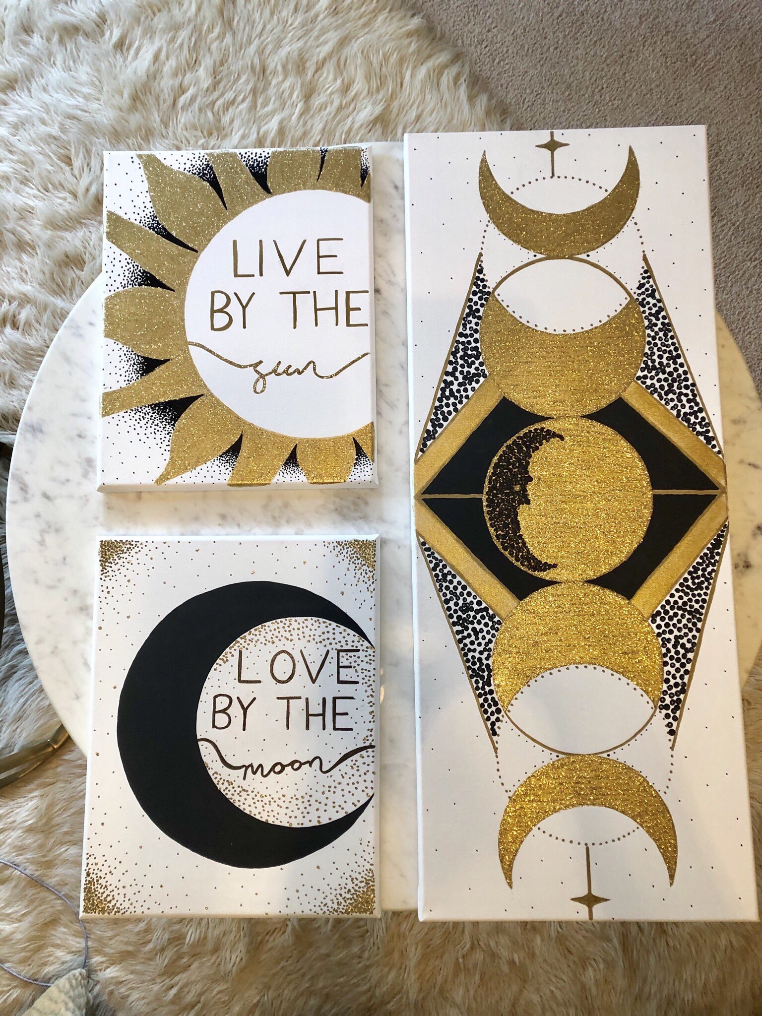 A larger scale sun and moon collection. All on wrapped canvas the gold sun and moon canvas sit to the left of a larger and wider canvas with a slightly more geometric version of the gold moon phases.